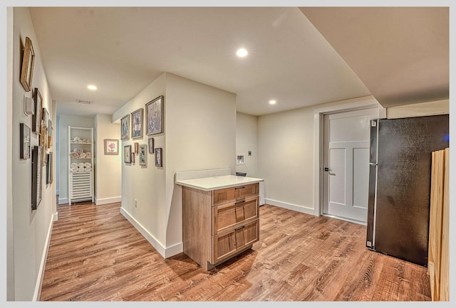 hallway with light wood-style floors, baseboards, and recessed lighting