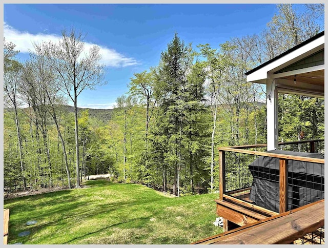 view of grassy yard featuring a wooded view and a wooden deck