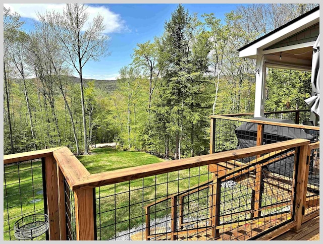 wooden deck with a yard and a forest view