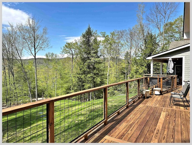 wooden terrace featuring a yard and a wooded view
