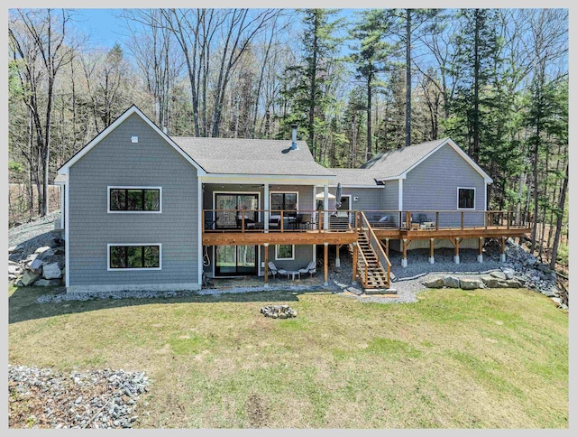 rear view of property with a deck, stairs, a lawn, and a shingled roof