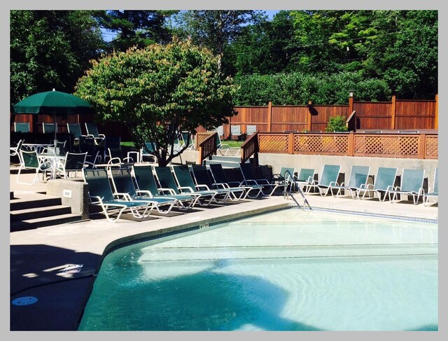 community pool with fence and a patio area