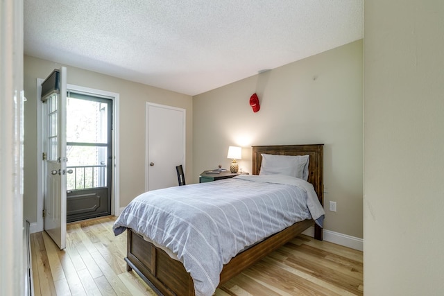 bedroom with light wood-style flooring, baseboards, and a textured ceiling