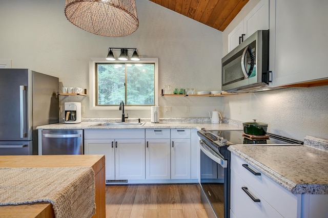 kitchen with appliances with stainless steel finishes, a sink, lofted ceiling, open shelves, and light countertops