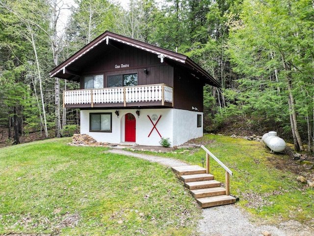 chalet / cabin featuring a front lawn, a wooden deck, and a wooded view