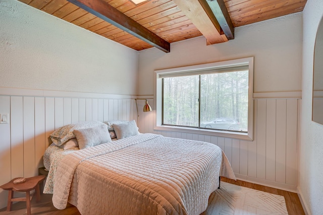 bedroom with wood ceiling, wood finished floors, wainscoting, and beam ceiling