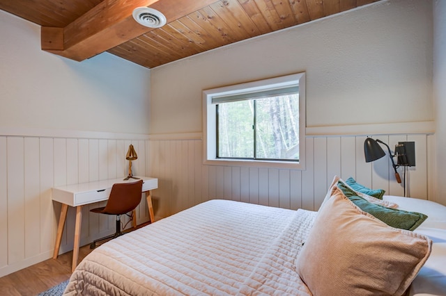bedroom featuring wood ceiling, wood finished floors, a wainscoted wall, and beamed ceiling