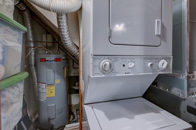 clothes washing area featuring stacked washing machine and dryer and electric water heater