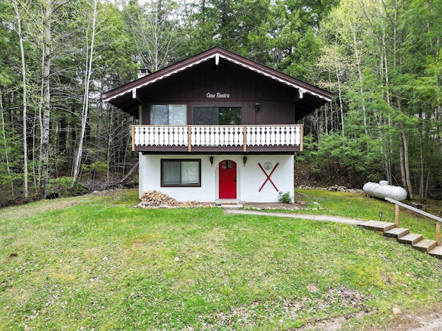 chalet / cabin with a front yard, a forest view, and a wooden deck