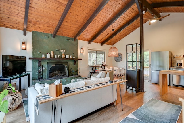 living area with wooden ceiling, beamed ceiling, a fireplace, wood finished floors, and a ceiling fan
