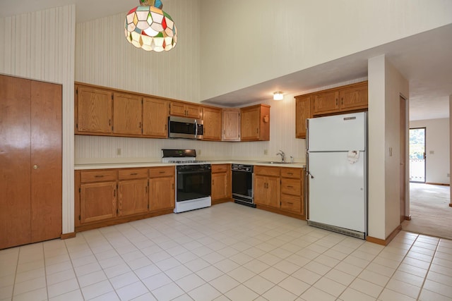 52 Ridgewood Dr Unit 14C, Atkinson, NH 03811 - kitchen featuring white appliances, light countertops, a sink, brown cabinetry, and a towering ceiling