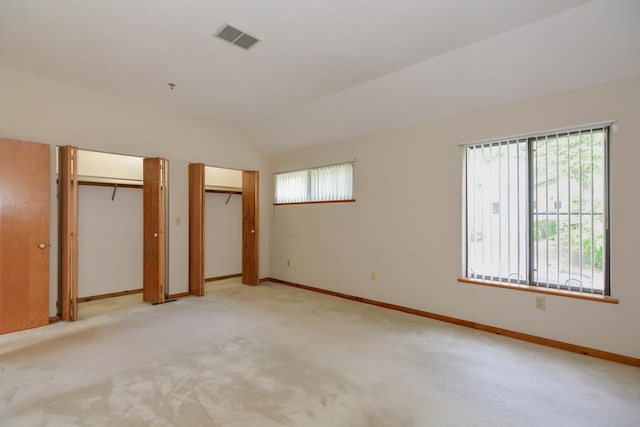 52 Ridgewood Dr Unit 14C, Atkinson, NH 03811 - unfurnished bedroom featuring two closets, lofted ceiling, baseboards, and light carpet