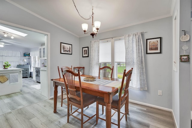 dining space featuring light wood-type flooring, a chandelier, ornamental molding, baseboards, and a ceiling fan