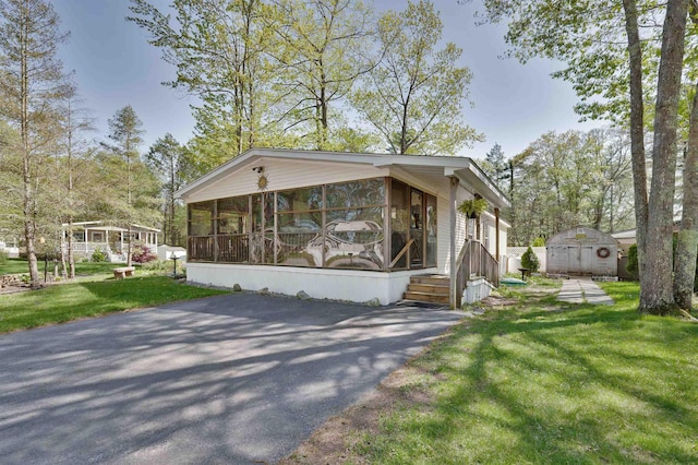 view of front of home featuring a sunroom, an outdoor structure, a shed, and a front lawn