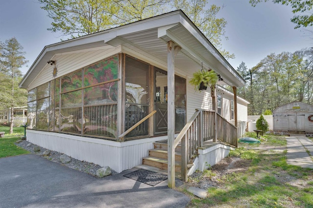 view of property exterior with a sunroom, a storage unit, and an outdoor structure