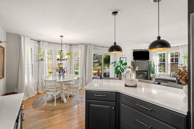 kitchen with plenty of natural light, light wood-style flooring, light countertops, and a glass covered fireplace