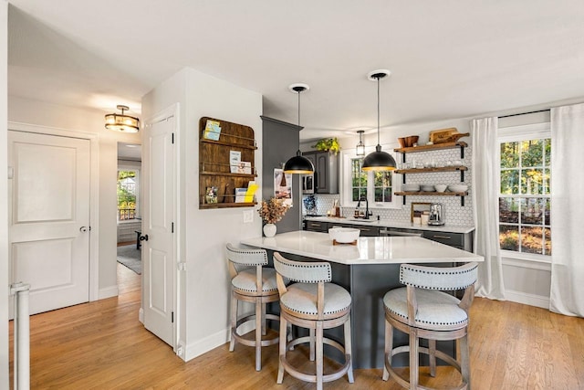kitchen featuring a sink, baseboards, light countertops, a kitchen breakfast bar, and light wood-style flooring