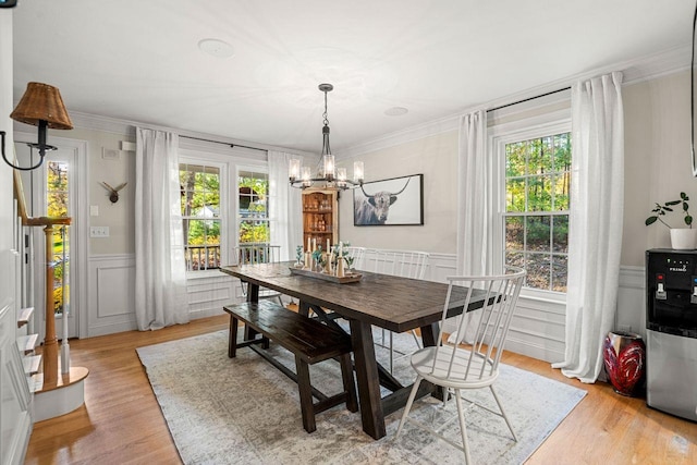 dining room with a decorative wall, a chandelier, plenty of natural light, ornamental molding, and light wood-type flooring