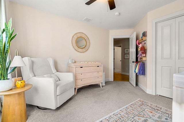 sitting room featuring light colored carpet, a ceiling fan, and baseboards