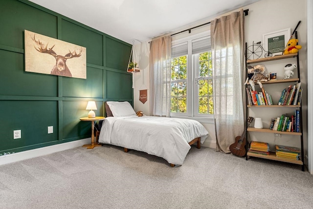 carpeted bedroom featuring a decorative wall and baseboards