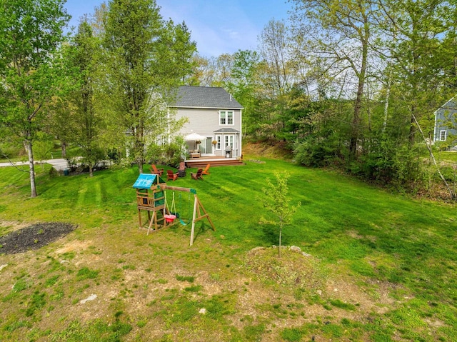 view of grassy yard with a playground and a deck