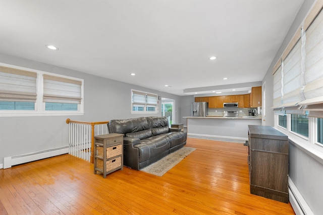 living room with a baseboard radiator, light wood-style floors, a baseboard heating unit, and recessed lighting