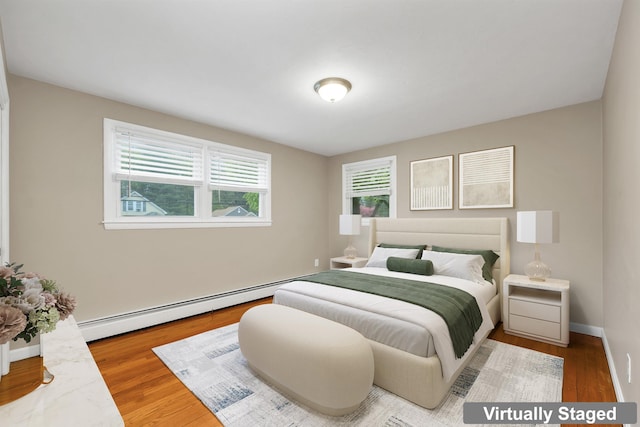 bedroom featuring a baseboard heating unit, wood finished floors, and baseboards