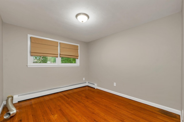 spare room with a baseboard radiator, wood finished floors, and baseboards