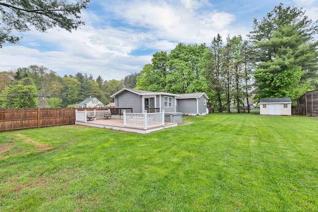 back of property with a shed, an outbuilding, a wooden deck, and view of wooded area