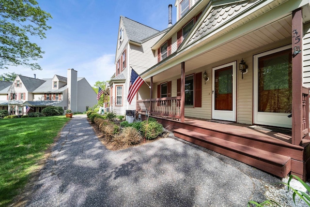 property entrance with a residential view, a porch, and a lawn