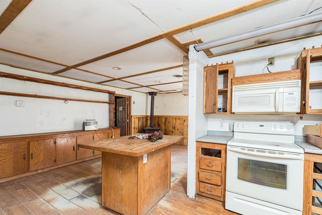 kitchen with white appliances, a wood stove, a wainscoted wall, wooden walls, and butcher block counters