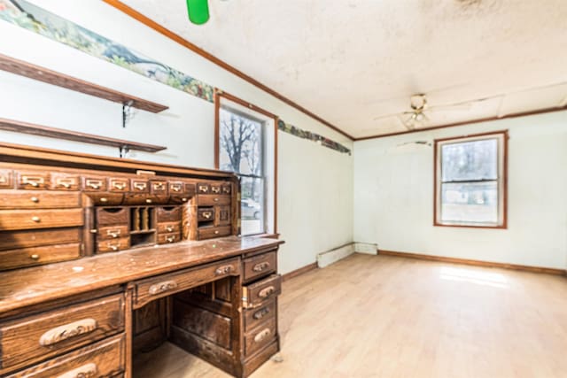 unfurnished office with light wood finished floors, a ceiling fan, crown molding, and baseboards