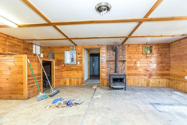 unfurnished living room featuring a wood stove, electric panel, and wood walls