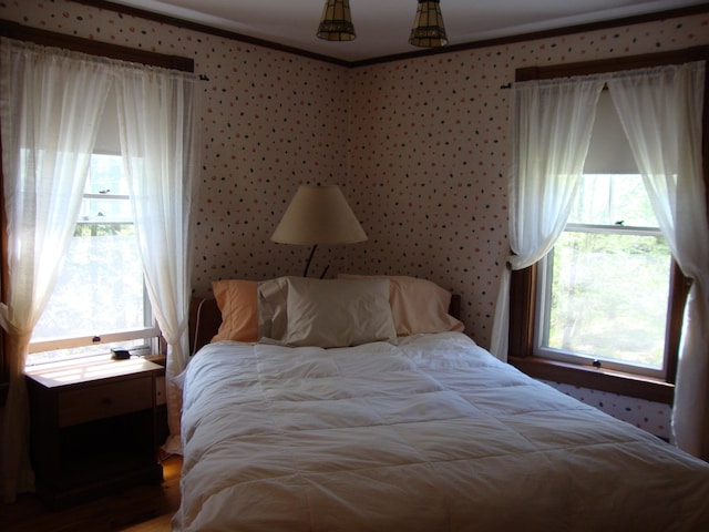 bedroom featuring ornamental molding and wood finished floors