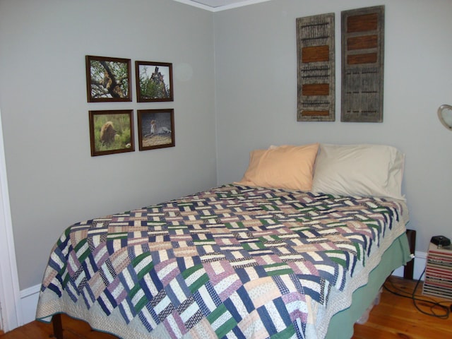 bedroom with wood finished floors and crown molding