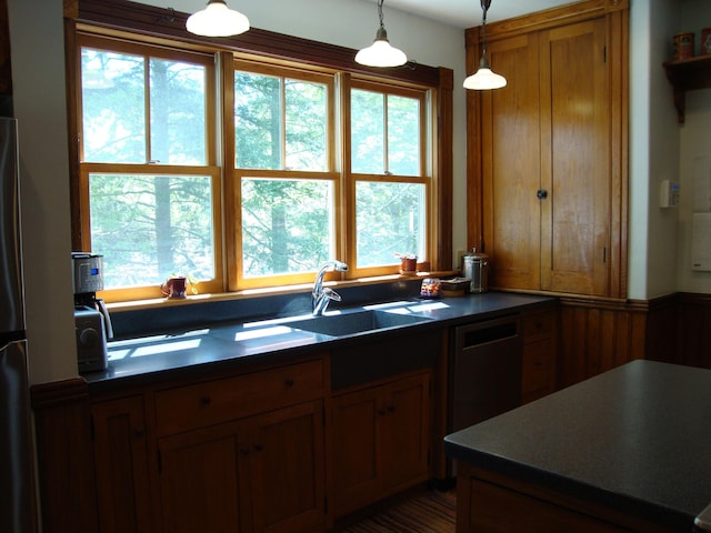 kitchen featuring a sink, brown cabinets, dark countertops, and decorative light fixtures