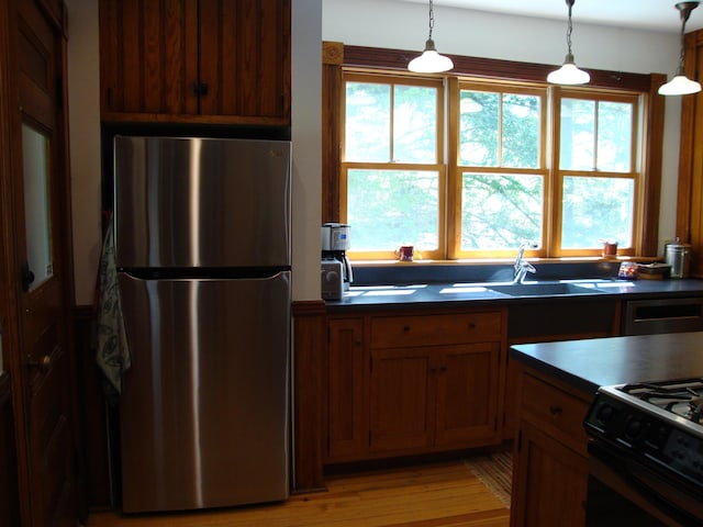kitchen featuring freestanding refrigerator, a sink, dark countertops, and healthy amount of natural light