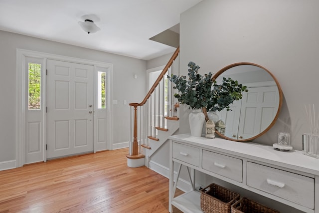 foyer with light wood-style floors, stairs, and baseboards