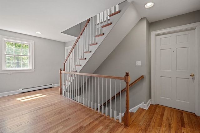 staircase with a baseboard heating unit, wood finished floors, baseboards, and recessed lighting