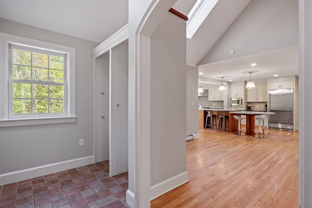 hall with baseboards, a skylight, vaulted ceiling, recessed lighting, and a baseboard heating unit