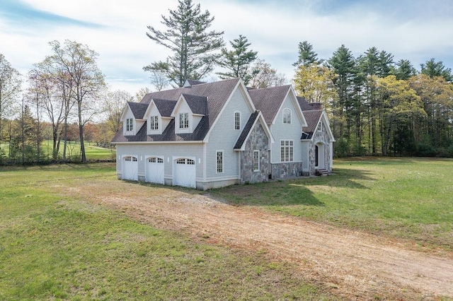 view of front of property featuring driveway, a garage, a front lawn, and stone siding