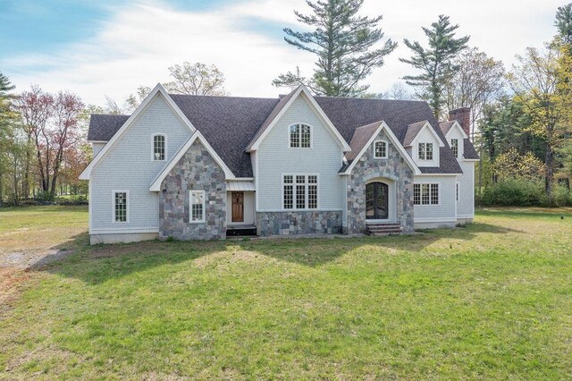 view of front of house with stone siding, a chimney, a front yard, and entry steps