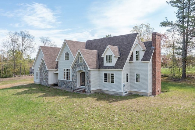 view of front of home featuring a chimney, a front lawn, a shingled roof, and stone siding