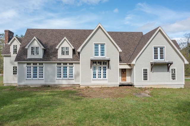 view of front of property with roof with shingles, a front yard, and a chimney