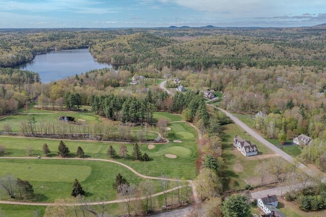 aerial view of property's location with a large body of water, a heavily wooded area, and a golf club