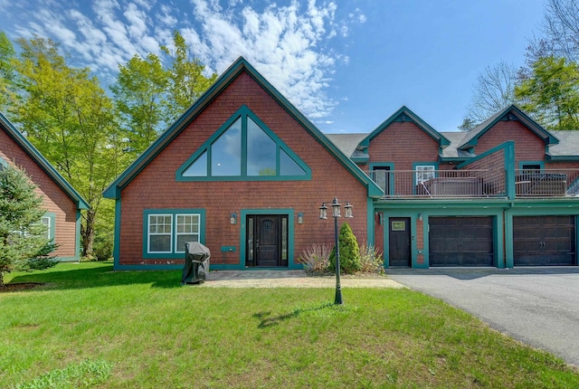 rear view of house featuring a balcony, asphalt driveway, and a lawn