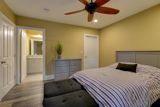 bedroom with wood finished floors, recessed lighting, ensuite bath, a ceiling fan, and a sink