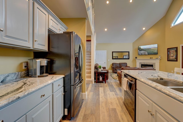 kitchen featuring light wood-type flooring, open floor plan, a fireplace, dishwasher, and recessed lighting