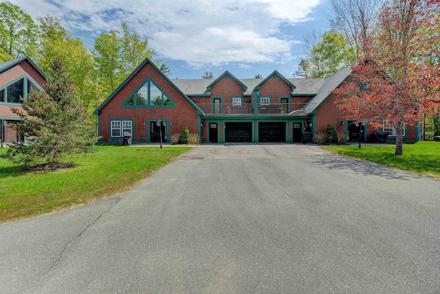 view of front of property featuring a balcony, driveway, a front lawn, and an attached garage