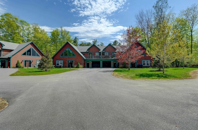 view of front of house with driveway, a front lawn, an attached garage, and a balcony